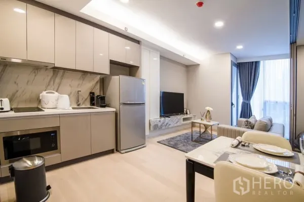 Condominium for rent in Khlong Toei, Bangkok - Fitted kitchen with glossy cabinetry, marble backsplash and an adjacent dining area.