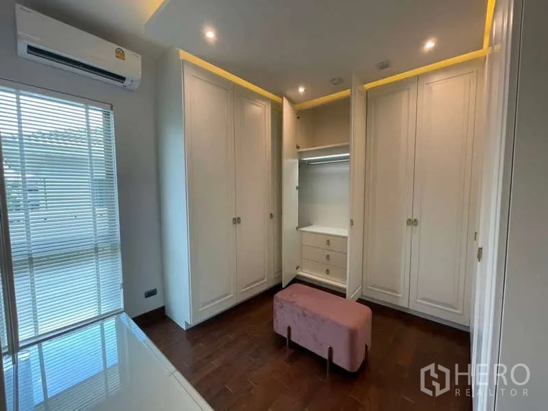 Detached House for rent or sale in Lat Krabang, Bangkok - Walk-in wardrobe with white built-in closets, open section and a pink bench.