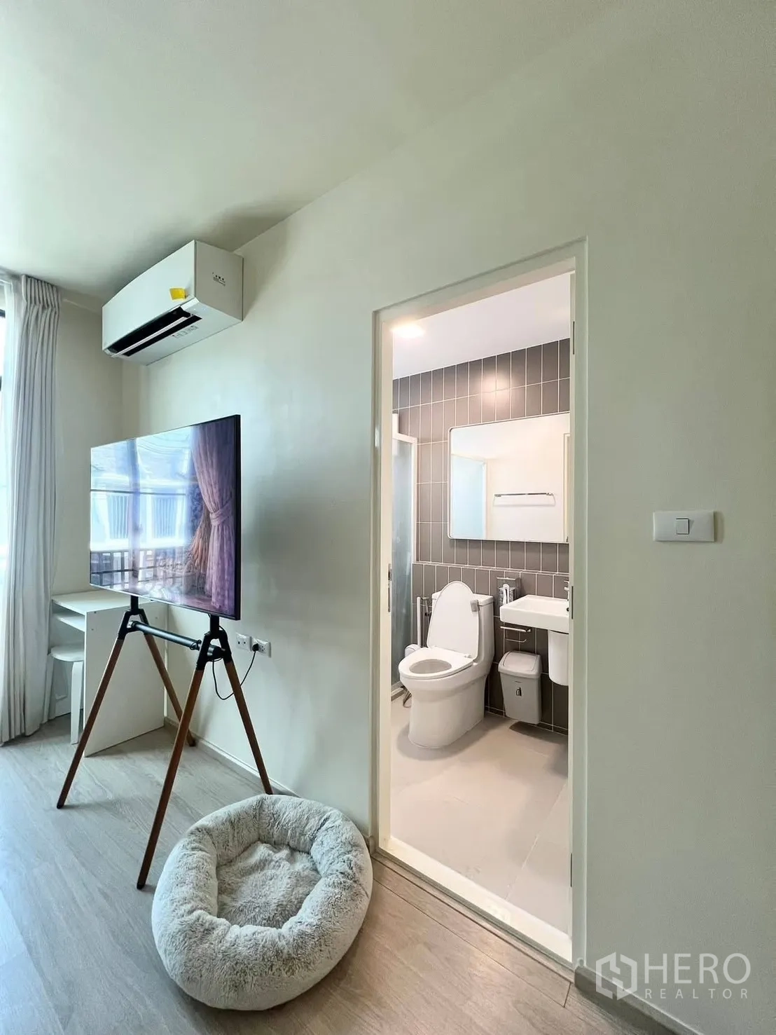 ทาวน์เฮาส์ for rent in Bang Phli, Samut Prakan - พื้นที่นั่งเล่นติดประตูห้องน้ำ มีแอร์ ทีวีตั้งบนขาตั้ง และผ้าม่าน
