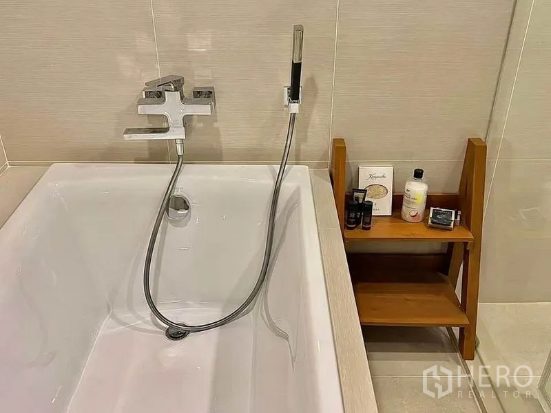 คอนโด ให้เช่าหรือขายในBang Na, Bangkok - อ่างอาบน้ำสมัยใหม่พร้อมฝักบัวสายอ่อนและชั้นวางของไม้ในห้องน้ำ