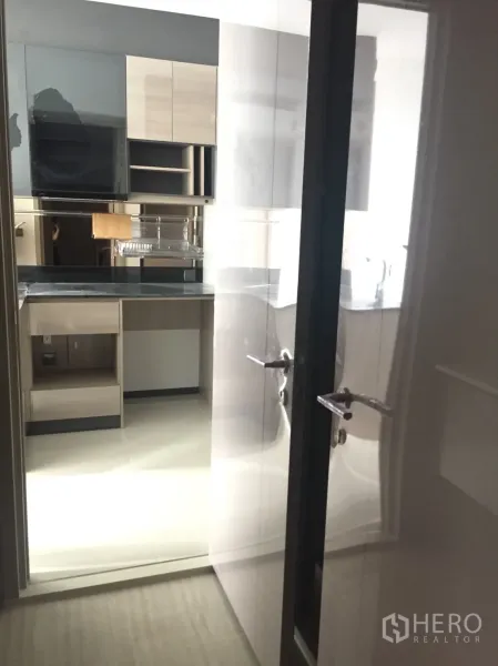 Condominium for sale in Din Daeng, Bangkok - Bright kitchenette viewed through glossy sliding door with upper cabinets and counter space.