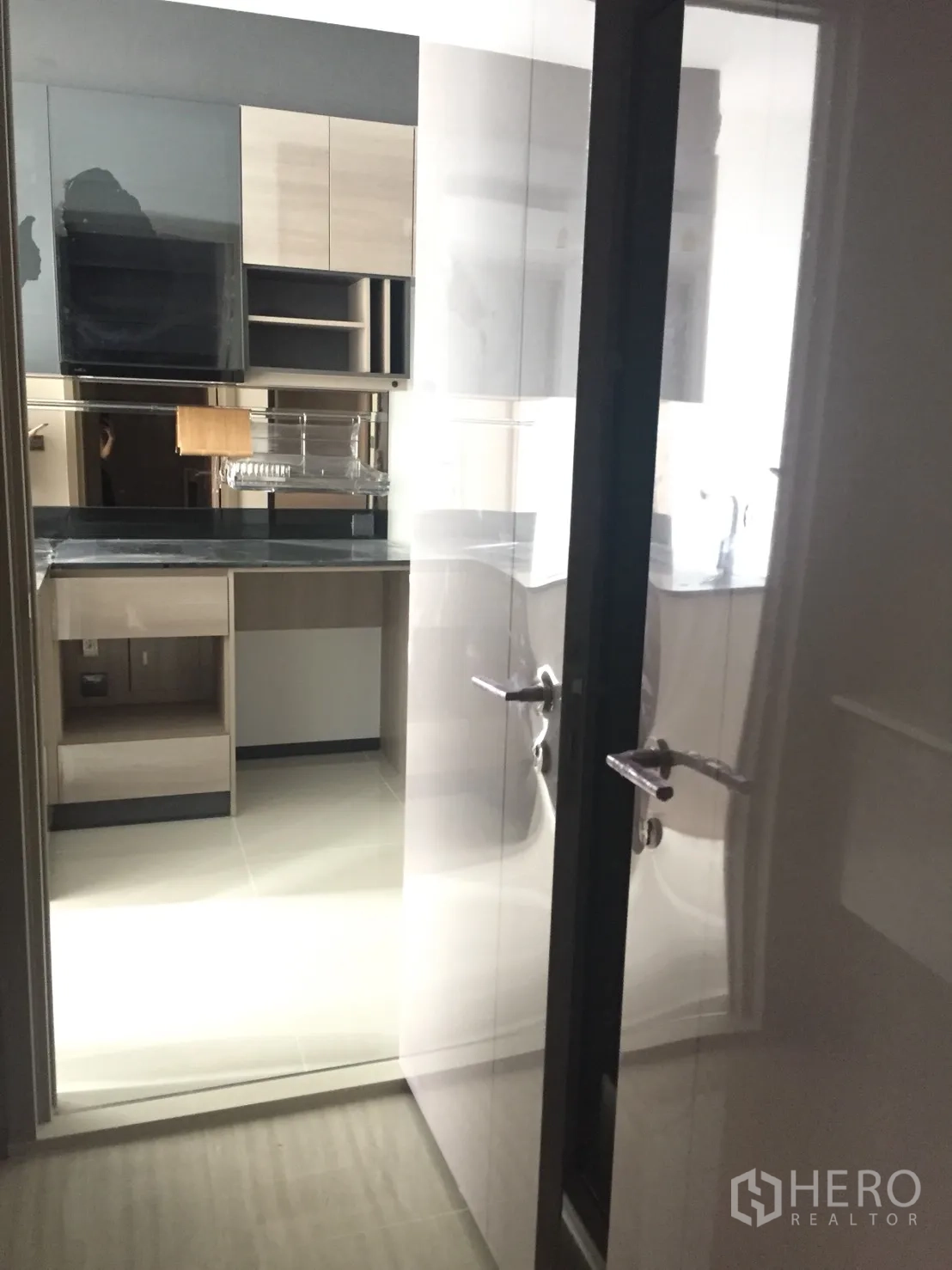 Condominium for sale in Din Daeng, Bangkok - Bright kitchenette viewed through glossy sliding door with upper cabinets and counter space.