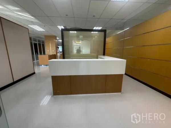 Office Space for rent in Suan Luang, Bangkok - Reception area with an L-shaped white desk and wood-paneled wall behind.
