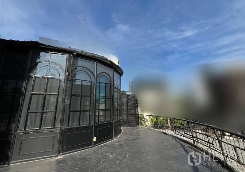 Retail Space for rent - Side view of the arched glass façade with a wide terrace walkway and railing.