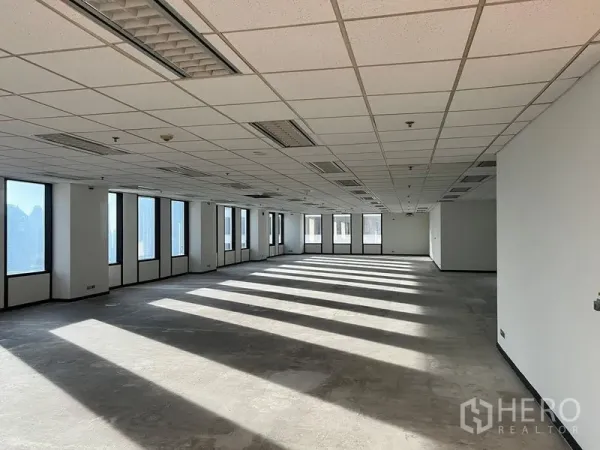 Office Space for rent in Khlong Toei, Bangkok - Unfurnished office space with rows of tall windows, suspended ceiling, lighting panels and air‑conditioning vents, filled with natural light.