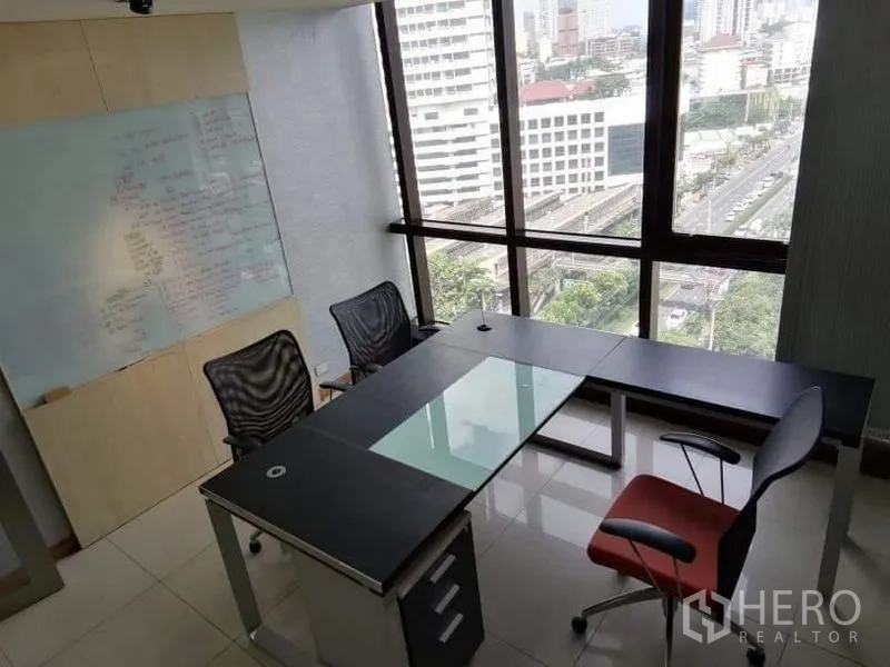 Office Space for rent - Corner office with L-shaped workstation and floor-to-ceiling windows offering skyline views.