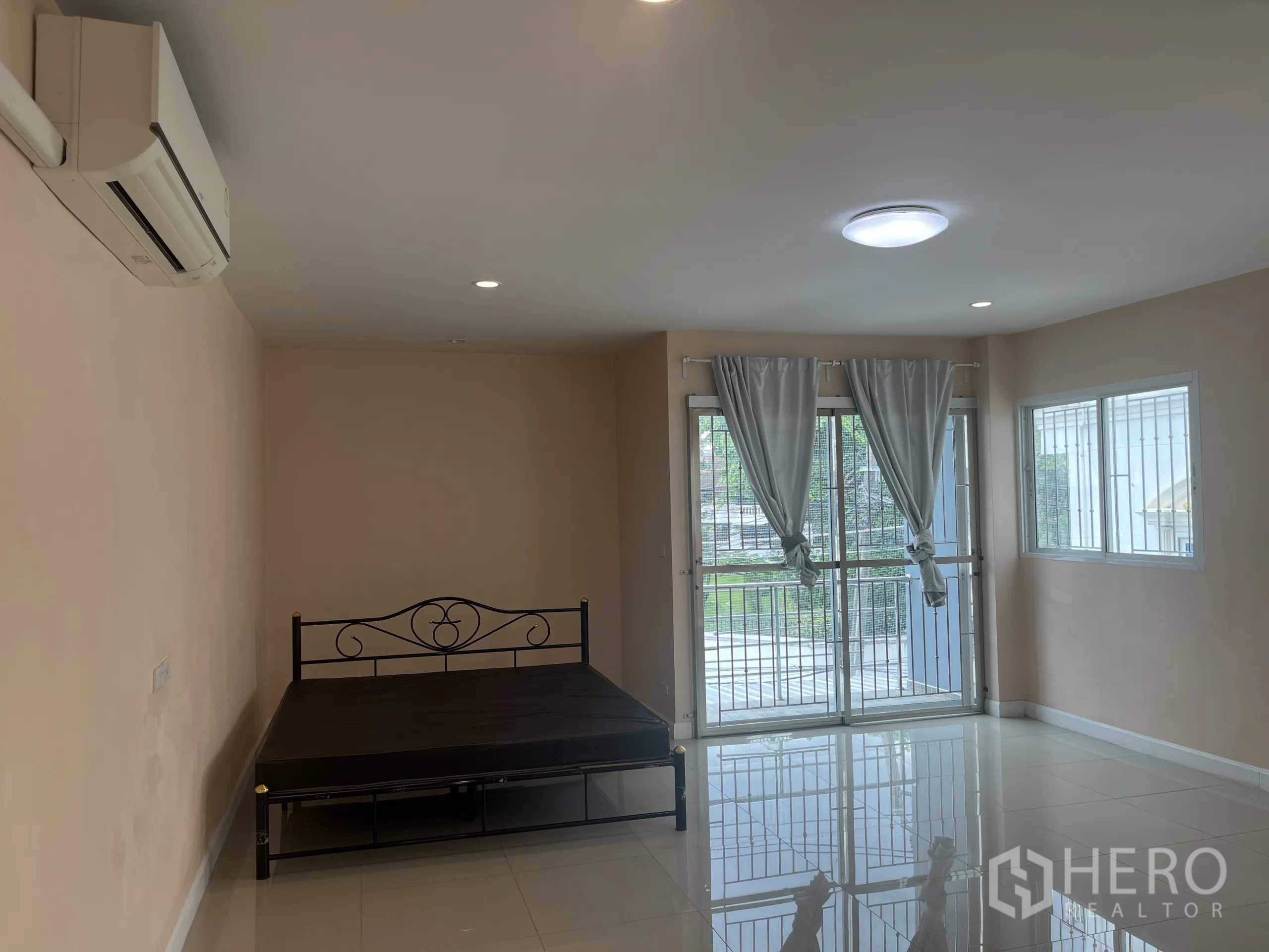 Townhouse for rent in Huai Khwang, Bangkok - Air-conditioned bedroom with balcony doors, curtains and polished tiled flooring.