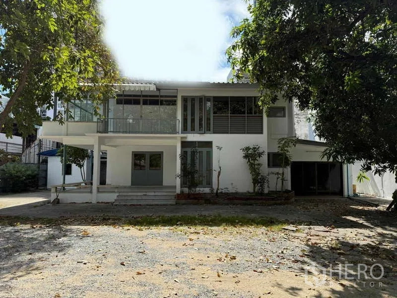 Detached House for rent in Watthana, Bangkok - Front elevation of the detached house with wide gravel driveway and garden.
