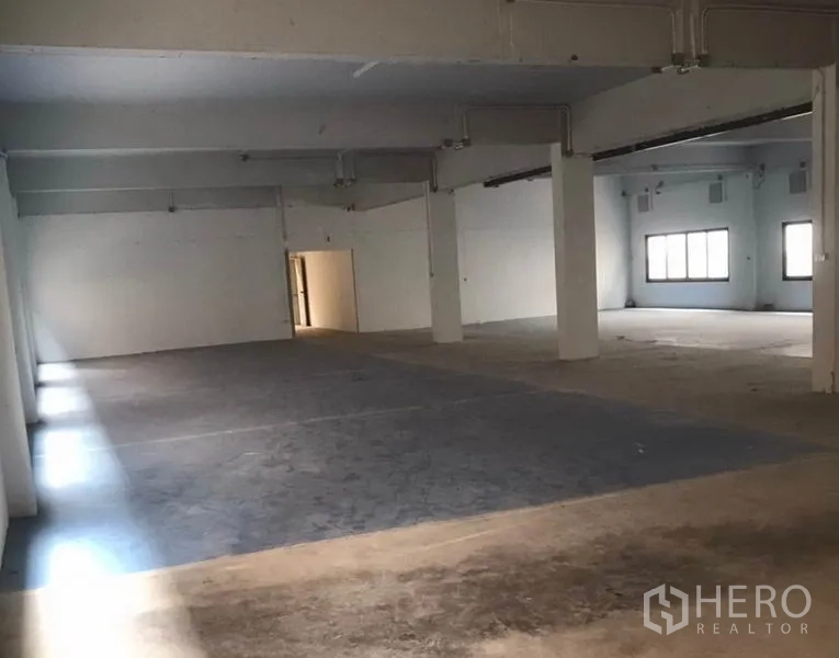 Factory for rent in Bang Bua Thong, Nonthaburi - Expansive factory hall with pillars, multiple zones and a doorway to the rear area.