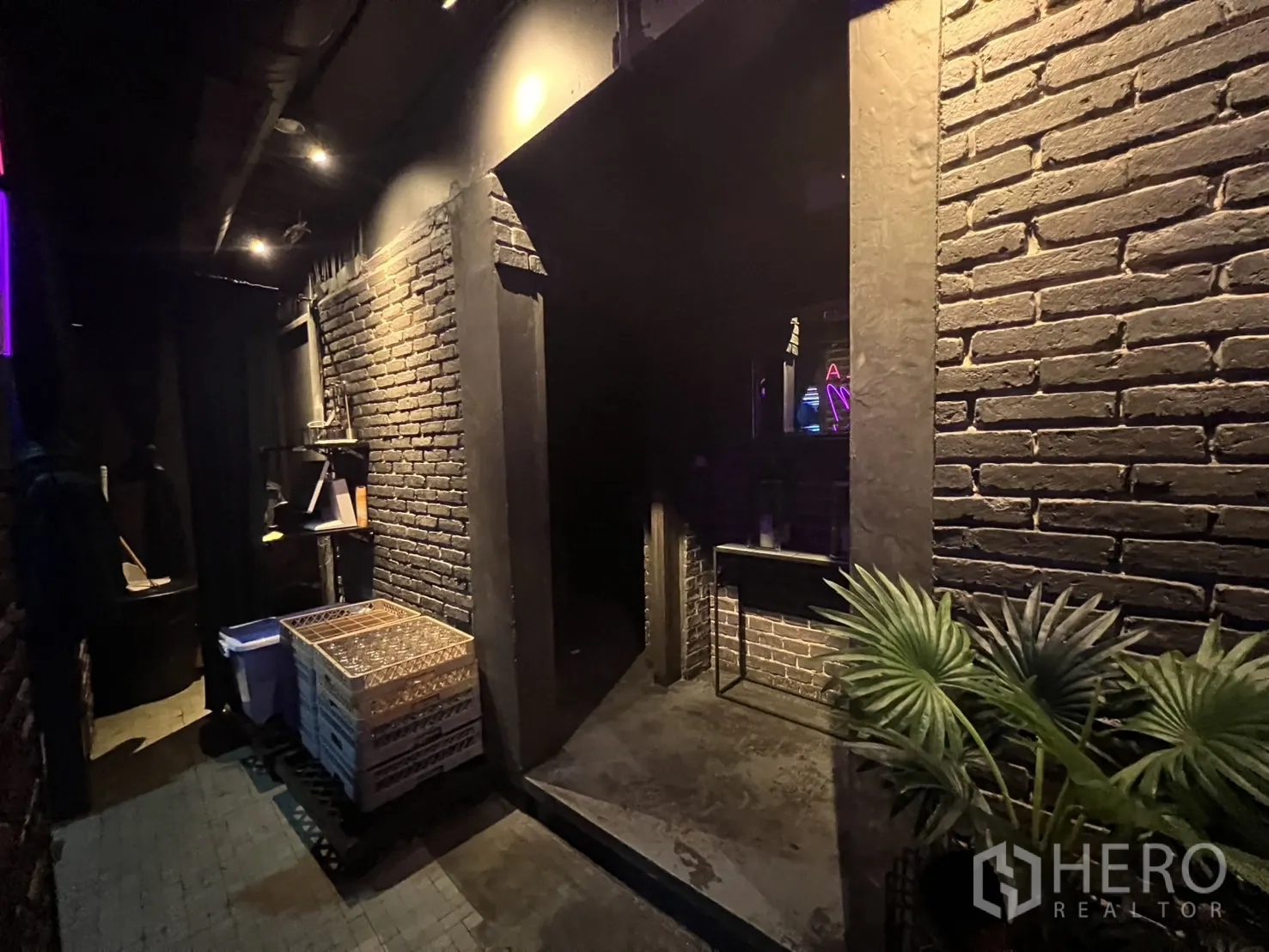Retail Space for rent in Bangkok - Service corridor with exposed brick, doorway to bar and potted plant.