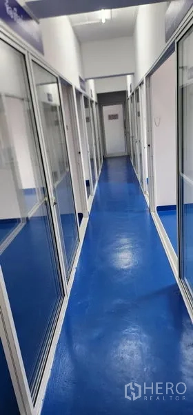 Warehouse for rent in Bueng Kum, Bangkok - Bright corridor with blue epoxy floor and glass-partitioned rooms in a warehouse.