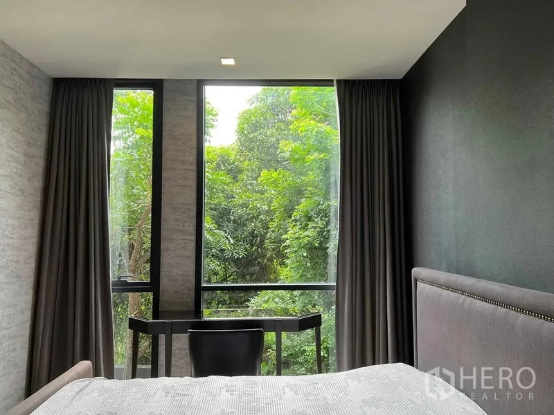 公寓 出租在Watthana, Bangkok - 卧室内的书桌面向高窗，窗外绿树成荫。