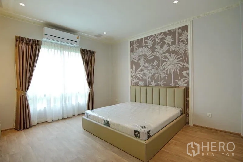 独立式住宅 出租在Lat Krabang, Bangkok - 客卧，热带图案背景墙、窗帘与浅木地板。