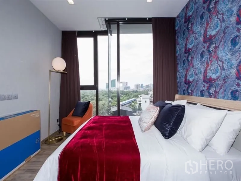 公寓 出租在Chatuchak, Bangkok - 卧室设特色墙与落地窗，享城市与公园景观。