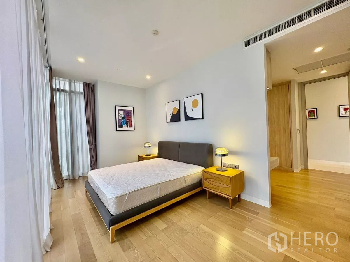 公寓 出租在Watthana, Bangkok - 转角主卧，木地板与床头柜，旁为套内卫生间入口。