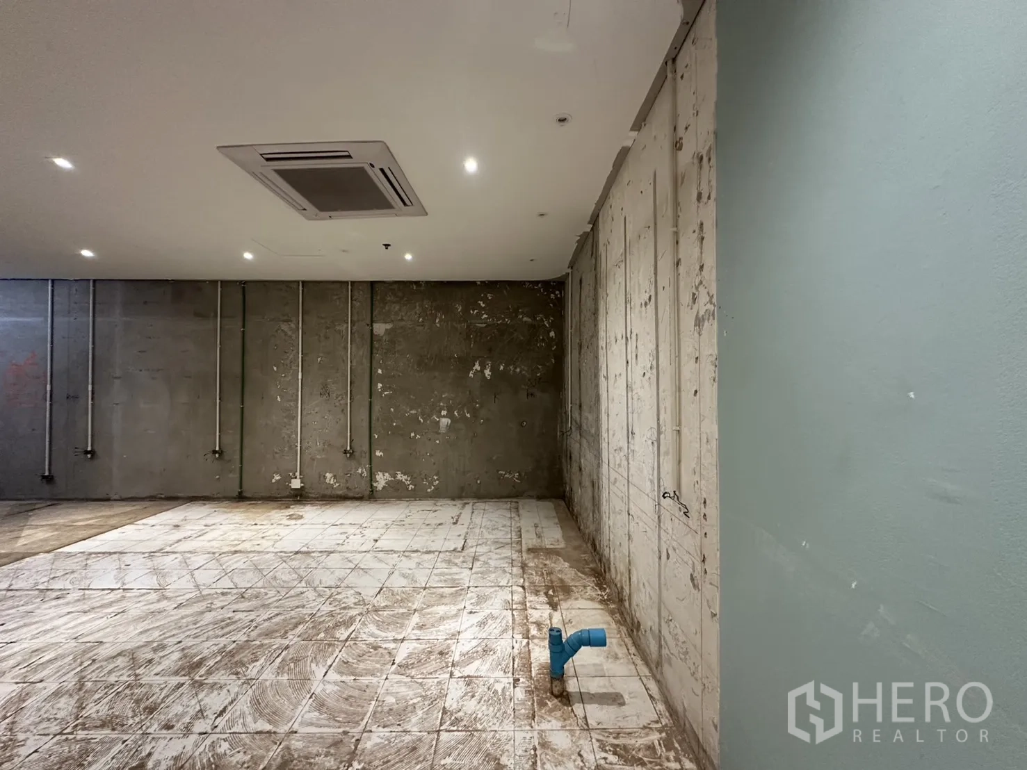 零售空间 for rent in Watthana, Bangkok - 零售毛坯区，混凝土墙上外露管线，天花嵌入空调，地面有管道预留口。