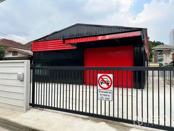 Warehouse for rent in Lat Phrao, Bangkok - Gated black-and-red warehouse exterior with red roller shutter and concrete loading yard.