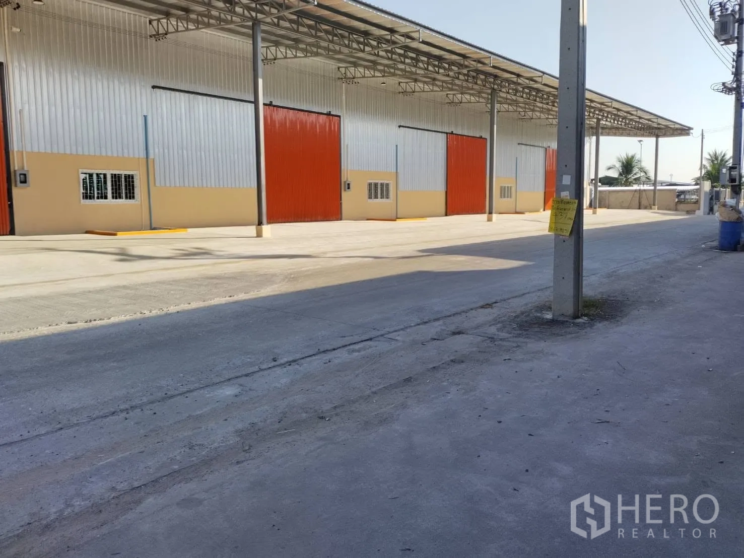 仓库 for rent in Khlong Luang, Pathum Thani - 仓库外观，带遮雨装卸区、多扇大型金属推拉门与宽阔混凝土场地
