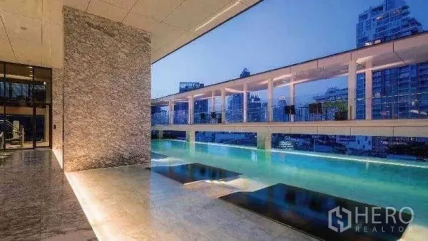 Condominium for rent or sale in Khlong Toei, Bangkok - Elevated condominium swimming pool with marble deck and panoramic city backdrop at dusk.