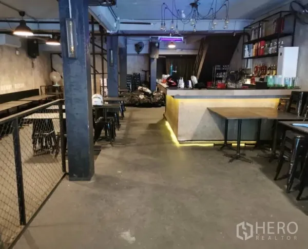 Shophouse for rent or sale in Watthana, Bangkok - Open-plan dining area with concrete floors, pendant lights and a service counter.
