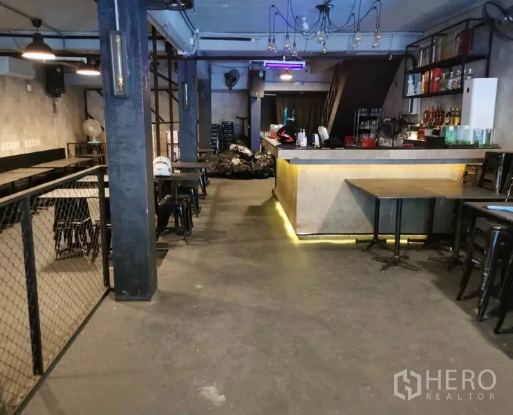 Shophouse for rent or sale in Watthana, Bangkok - Open-plan dining area with concrete floors, pendant lights and a service counter.