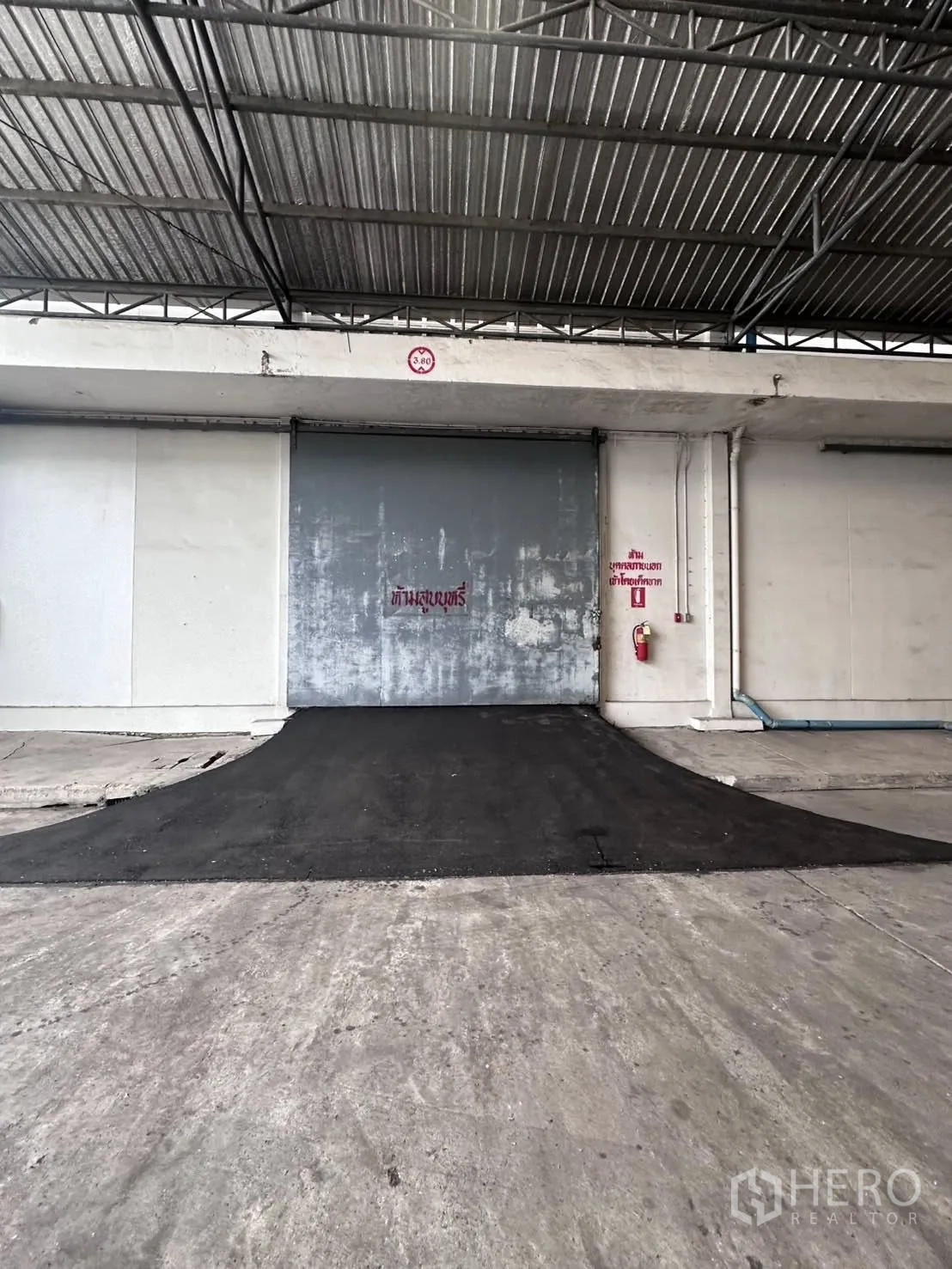 Warehouse for rent in Mueang Samut Prakan, Samut Prakan - Loading ramp leading up to a gray roller shutter door under a metal canopy.