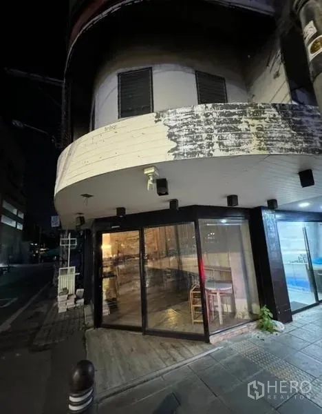 Retail Space for rent in Watthana, Bangkok - Night view of the corner unit showing illuminated glass facade and curved upper level.