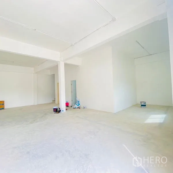 Warehouse for rent in Bang Khae, Bangkok - Large white room with concrete floor and supplies on the ground, ideal for office or staff area.