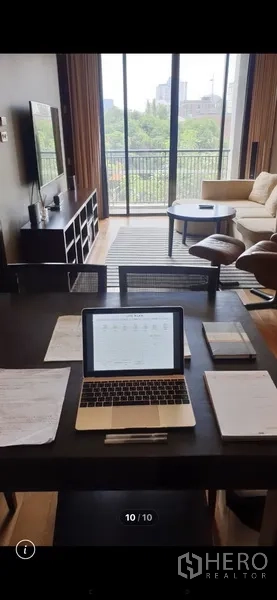 Condominium for rent in Watthana, Bangkok - Work-from-home dining table facing a bright living room with TV unit and a balcony opening to city-green views.