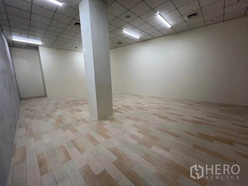 Retail Space for rent in Watthana, Bangkok - View across empty retail unit highlighting a central pillar, tiled flooring and white walls.