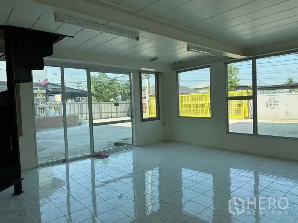 Warehouse for rent in Nakhon Pathom - Bright office room with tiled floor, large windows and sliding glass door overlooking the concrete yard.