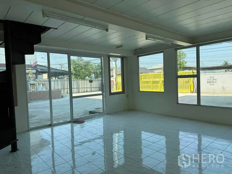 Warehouse for rent in Nakhon Pathom - Bright office room with tiled floor, large windows and sliding glass door overlooking the concrete yard.