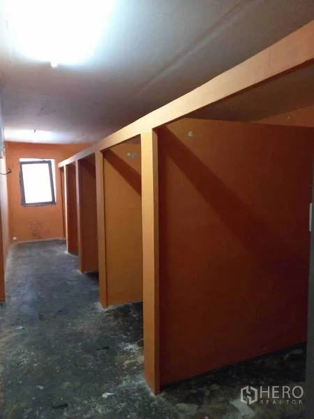 Shophouse for rent in Watthana, Bangkok - Row of orange partitioned rooms or booths along a narrow corridor.