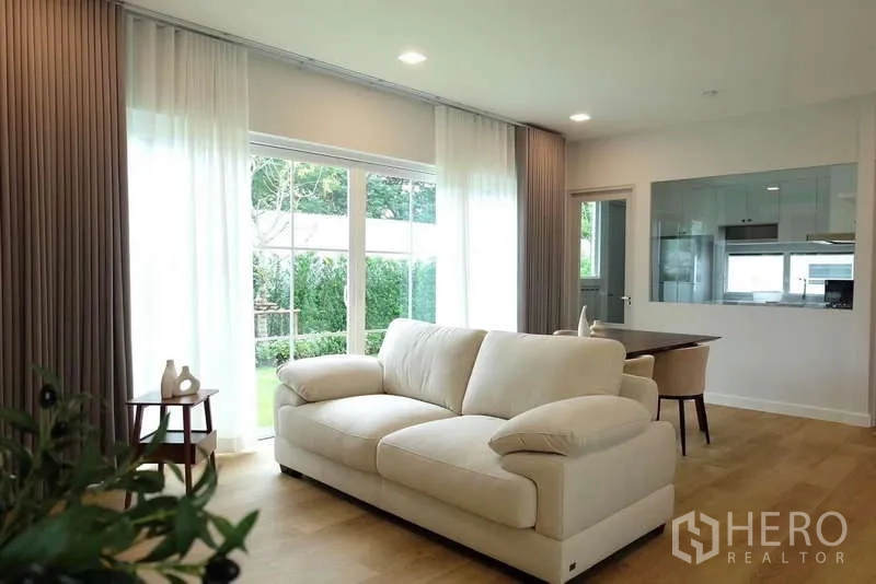 บ้าน ให้เช่าในBang Phli, Samut Prakan - ห้องนั่งเล่นสว่าง โซฟาสีครีม หน้าต่างบานใหญ่เห็นสวน