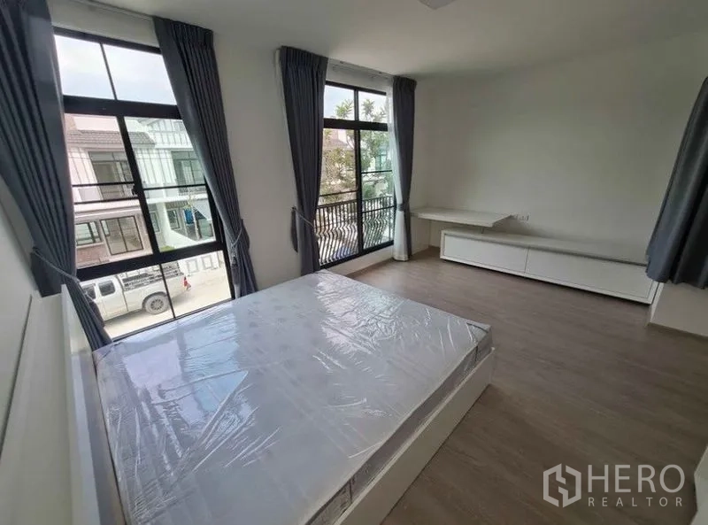 Townhouse for rent in Bang Phli, Samut Prakan - Upper bedroom with corner windows and small balcony railing overlooking the neighborhood.