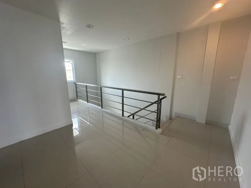 Home Office for rent in Bang Na, Bangkok - Upper corridor with metal railing and a side window.