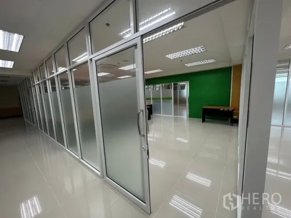Office Space for rent in Suan Luang, Bangkok - Sliding glass door with frosted panels leading to partitioned office rooms along a polished tile corridor.