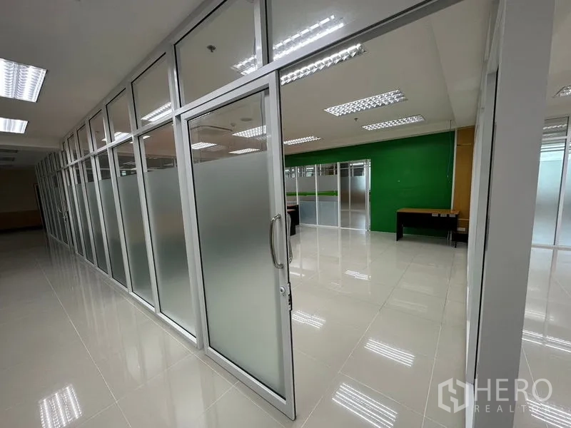 Office Space for rent in Suan Luang, Bangkok - Sliding glass door with frosted panels leading to partitioned office rooms along a polished tile corridor.