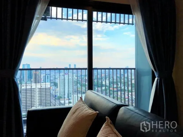 คอนโด ขายในSuan Luang, Bangkok - วิวเมืองจากระเบียง เห็นราวกันตก กรอบด้วยผ้าม่านและโซฟา