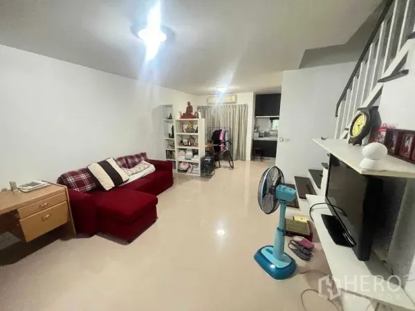 Townhouse for rent in Bueng Kum, Bangkok - Open-plan living room with red sofa, TV wall and staircase.