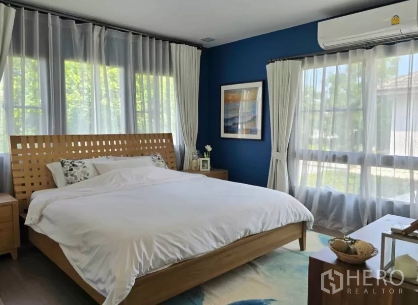 Detached House for rent in Bang Phli, Samut Prakan - Master bedroom with blue feature wall, large windows, sheer curtains and wooden bed