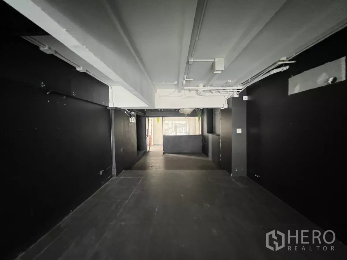Retail Space for rent in Watthana, Bangkok - Open interior view from the back showing white beams and black side walls.