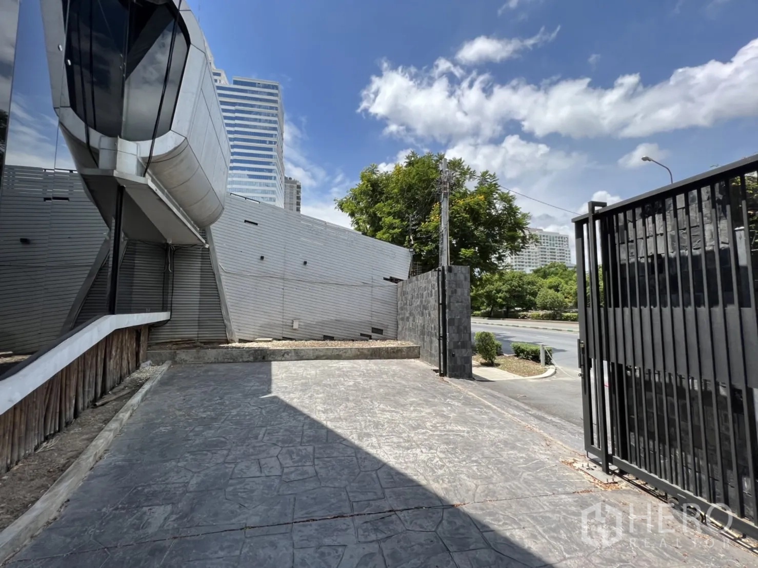 Retail Space for rent in Sathon, Bangkok - Secure gate and driveway beside a modern building, cityscape in the background.