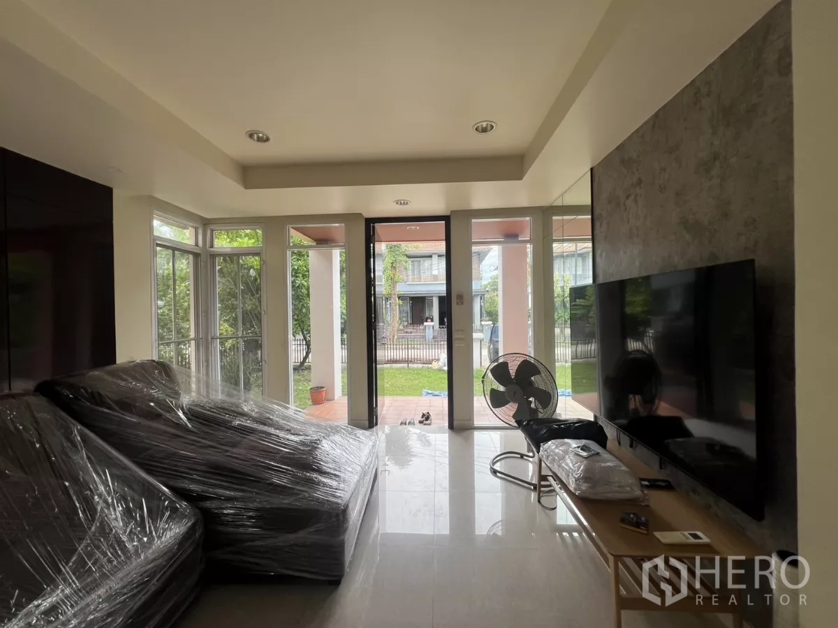 Detached House for rent in Wang Thonglang, Bangkok - Front garden with mature trees and metal fence along a quiet street.