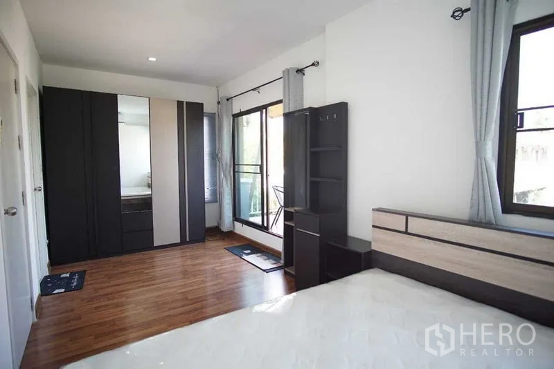 Townhouse for rent in Suan Luang, Bangkok - Bedroom with mirrored wardrobe, balcony door and ample natural light.