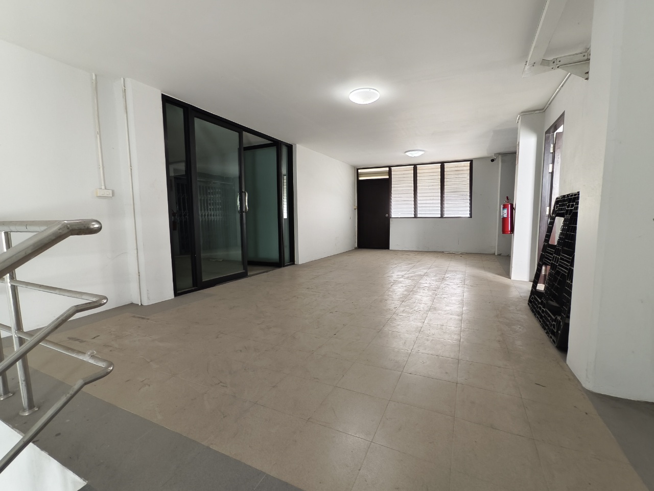 Warehouse for rent in Lat Krabang, Bangkok - Open office area with a glass partition beside the staircase and tiled flooring.