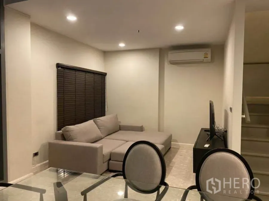 公寓 出租在Khlong Toei, Bangkok - 开放式客餐厅，L 型沙发、电视柜与旁侧楼梯。
