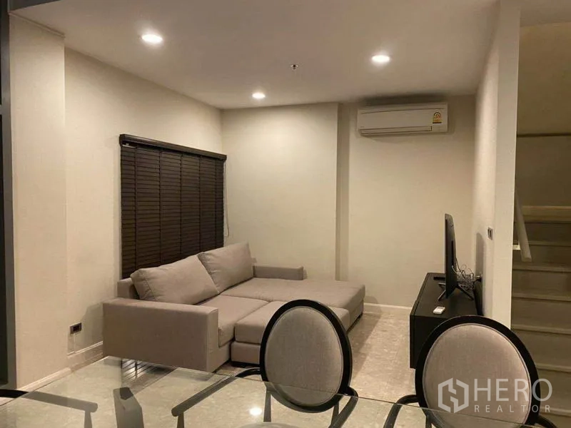 公寓 出租在Khlong Toei, Bangkok - 开放式客餐厅，L 型沙发、电视柜与旁侧楼梯。