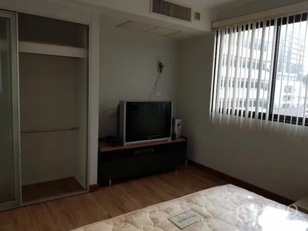 Condominium for rent in Watthana, Bangkok - Bright bedroom with TV console, open wardrobe, wood flooring and a window with city view blinds.