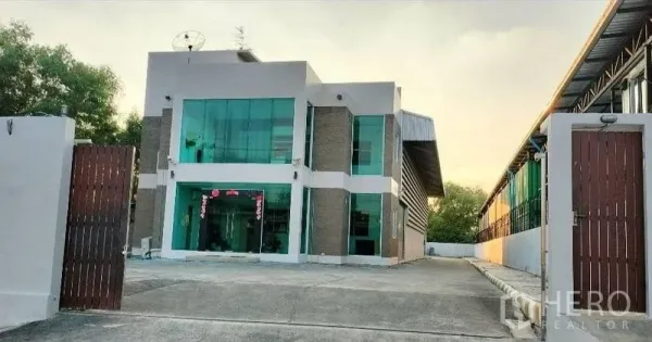 货栈 出租在Bang Bua Thong, Nonthaburi - 仓库外观正面，安全围墙、木门与宽敞前院停车区